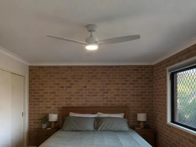Ceiling fan with light in a brick-walled bedroom with bed and windows in Gorokan