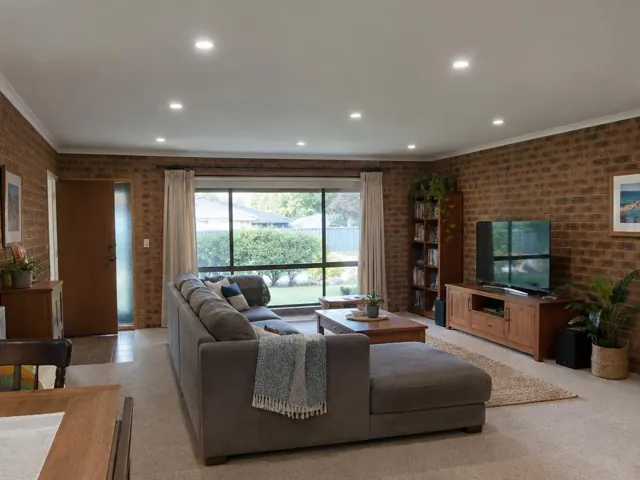 Living room with white ceiling and evenly spaced recessed downlights above brick walls in Lake Haven
